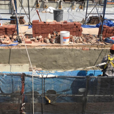 A construction worker diligently laying bricks on a wall, showcasing skill and focus in a building project.