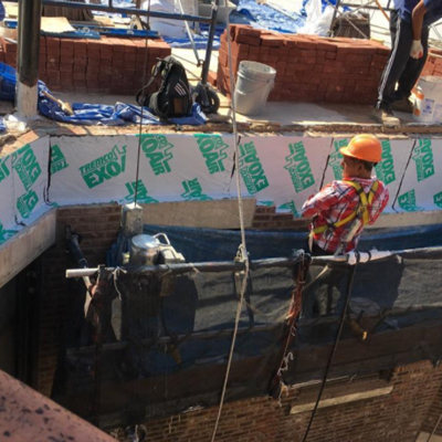 A team of construction workers on a roof, engaged in building tasks, showcasing teamwork and dedication to their project.